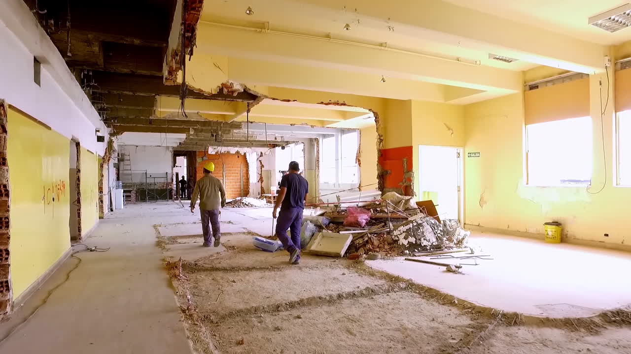Trabajadores de la construcción caminando por el interior de un edificio demolido.
