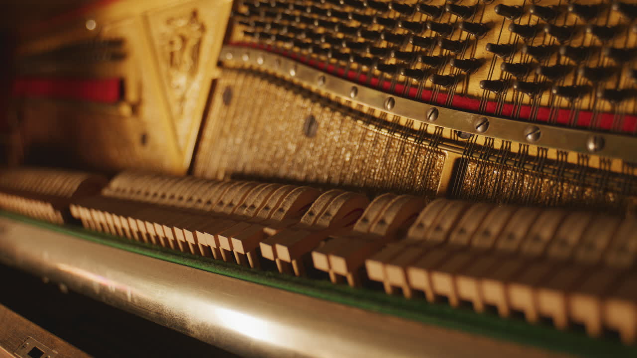 Movimento meccanico complesso di martelli di pianoforte in legno che colpiscono le corde in un ambiente caldo e artistico