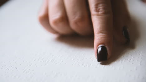 vista de cerca del dedo de una mujer ciega tocando las letras de un libro braille