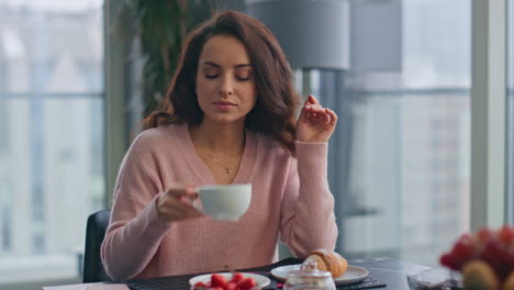 mujer tranquila bebiendo un capuchino disfrutando del desayuno en un cómodo primer plano de la cocina