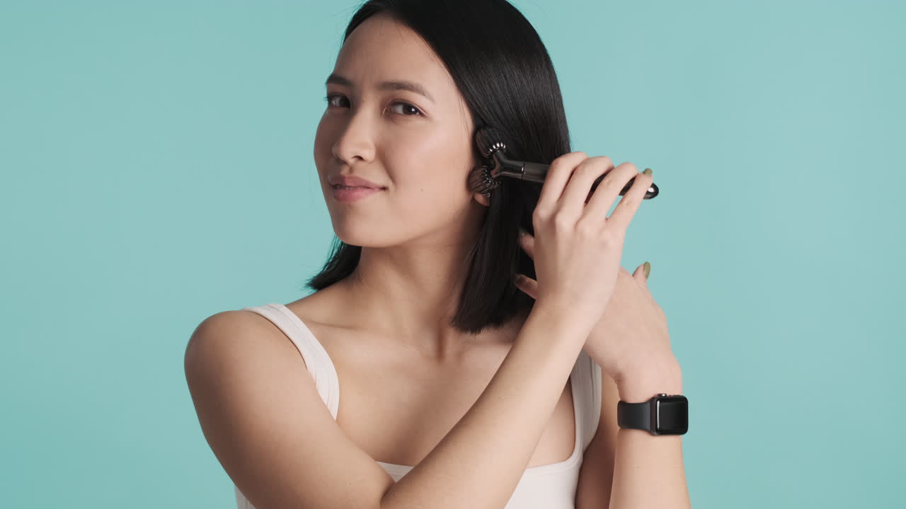 una mujer asiática masajeando su cara.