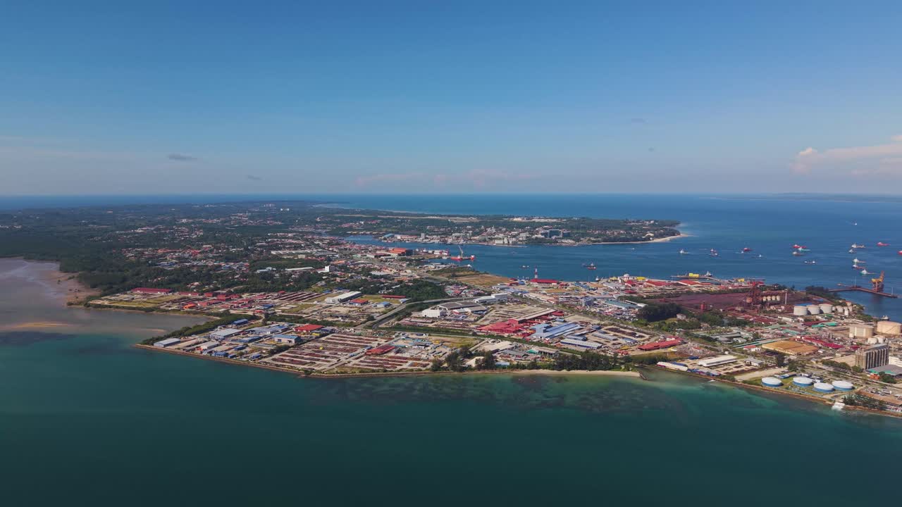 Drone shot of Rancha-Rancha Industrial Estate, Labuan, Malaysia, showing oil and gas terminals, storage tanks, and vessels along the tropical coast. Perfect for industry or energy footage
