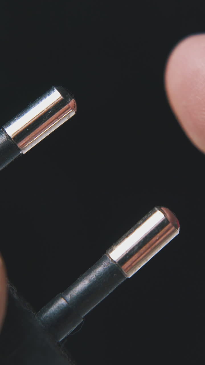 man demonstrates modern European plug in black plastic case on dark background extreme close view