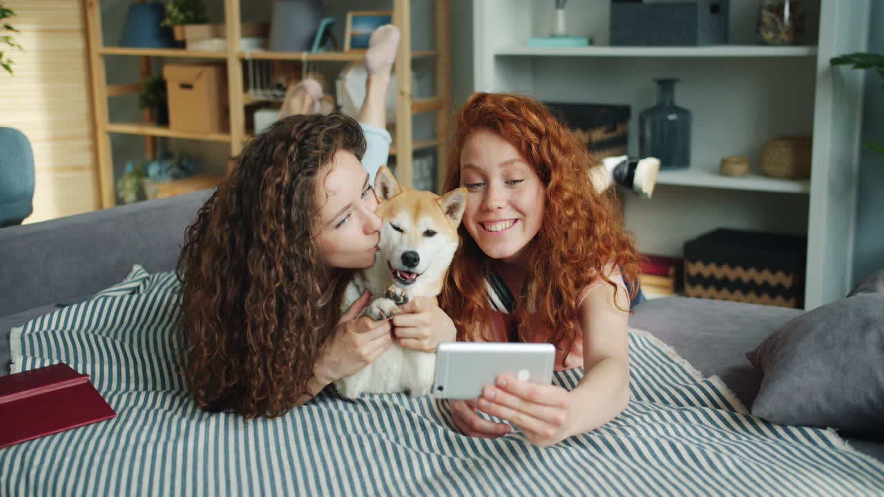 Two girls and a dog taking a selfie on a couch