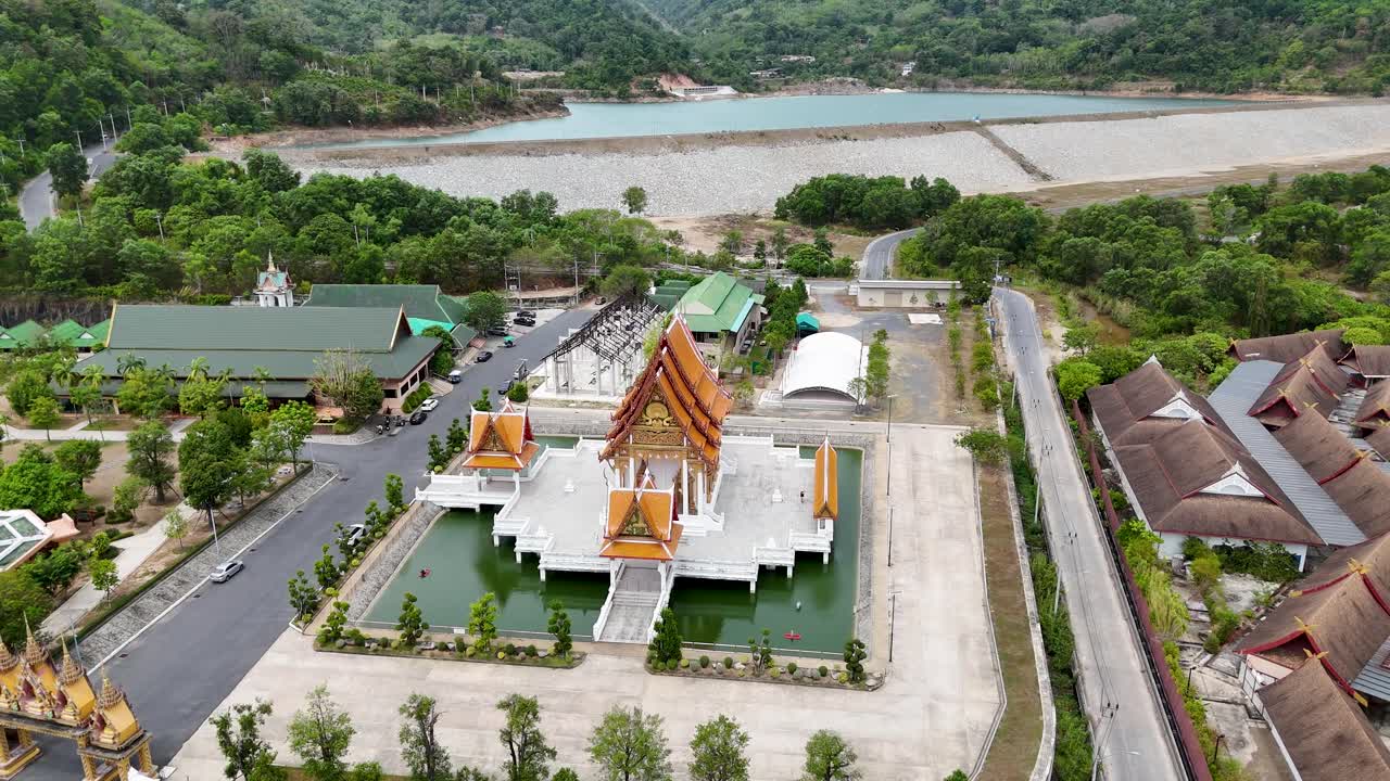las imágenes de drones capturan un sereno templo budista en phuket, tailandia, rodeado de exuberante vegetación y cuerpos de agua tranquilos.