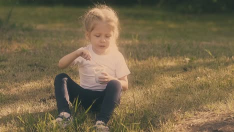 nice-young-lady-in-white-t-shirt-and-black-pants-eats-yogurt