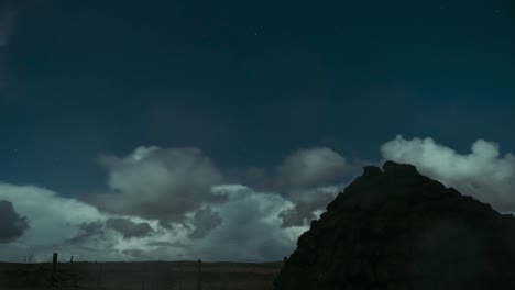 timelapse of clouds rolling past on a moonlit night with a peat stack in the foreground