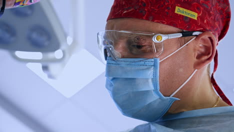 face of adult male surgeon in red cap, mask and special glasses. portrait of a medical professional at work. close up.