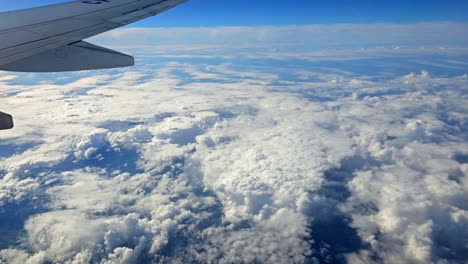 landscape stunning aerial view of fluffy cloud formations in atmosphere with aircraft wing of aeroplane from window at cruising altitude scenic weather sky landscape for travellers journey trip