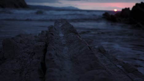 rocky seashore with waves at sunset