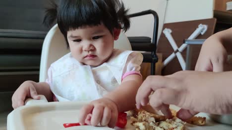 Asiatisches-Süßes-Mädchen,-Das-Ihr-Hausgemachtes-Essen-Auf-Dem-Babyfütterungsstuhl-Isst