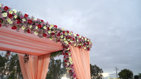 beautifully decorated outdoor wedding arch with variety of colourful flowers