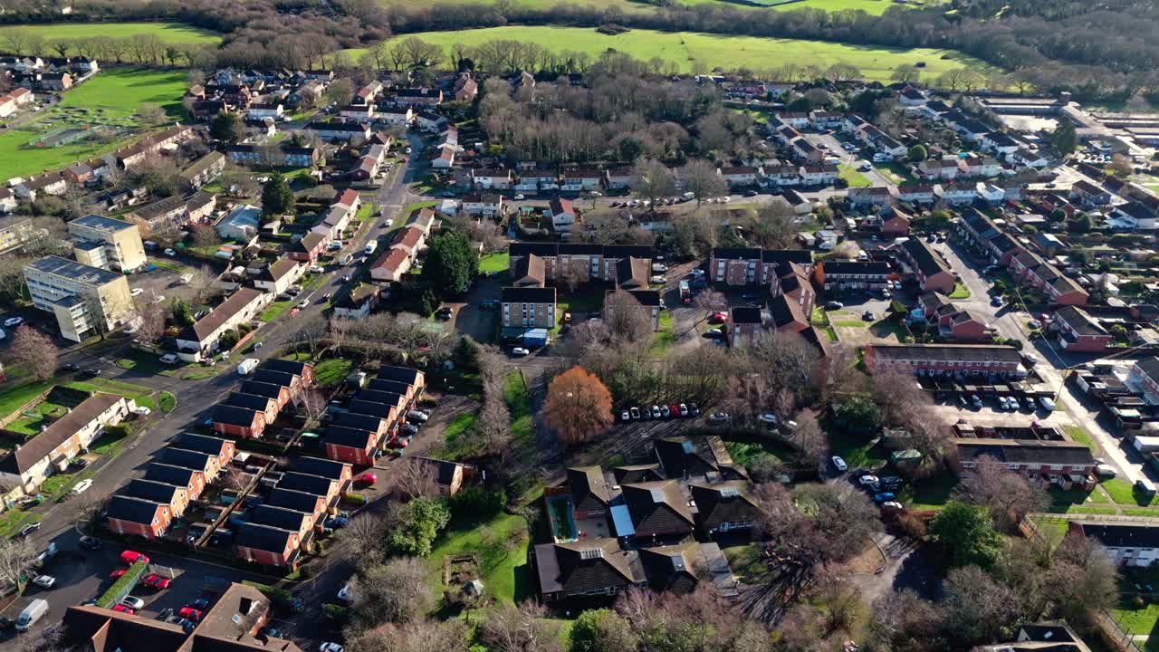Dronebillede i fugleperspektiv af Sholing, en region i Southampton, England. En smuk forstad med røde huse, haver, befærdede veje med trafik og biler under en smuk vintersolnedgang.