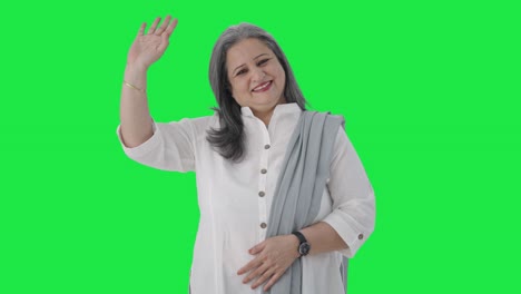 Happy-Indian-senior-businesswoman-waving-and-saying-Hello-Green-screen