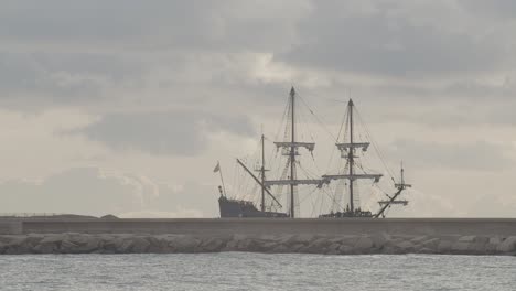 16th century galleon andalucia replica ship arriving at port in a beautiful cloudy day at sunrise behind a breakwater