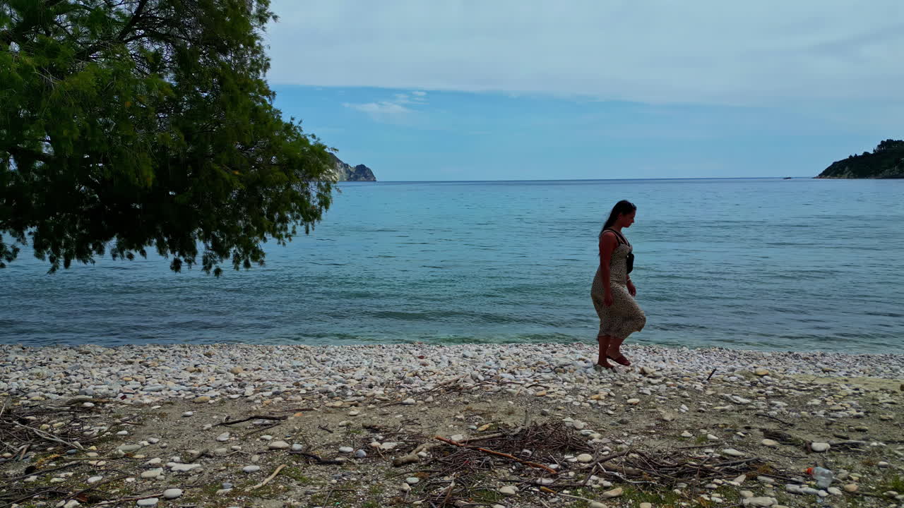 여름 드레스를 입은 매력적인 관광 여성이 그리스 해안, 면을 즐기고 있습니다.