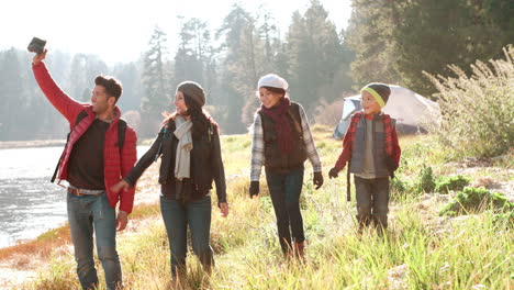 Parents-with-kids-walking-near-lake-admire-the-view-and-wave