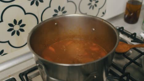 el chef agrega rollos de gelatina de arroz a la olla caliente con carne estofada y papas