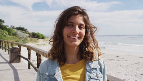 retrato de una mujer de raza mixta feliz de pie en un paseo soleado junto al mar sonriendo