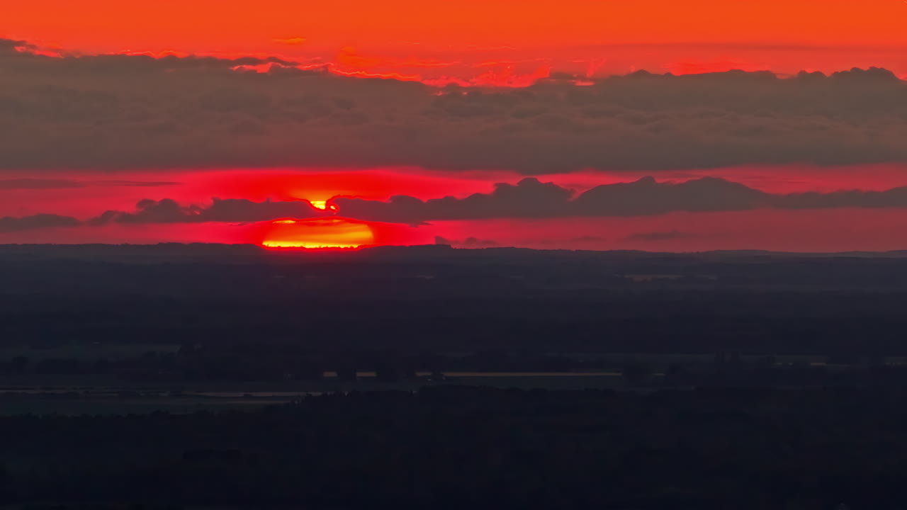 Sunset light glows orange ball sinking behind mountain ridge, silhouette glow scenic