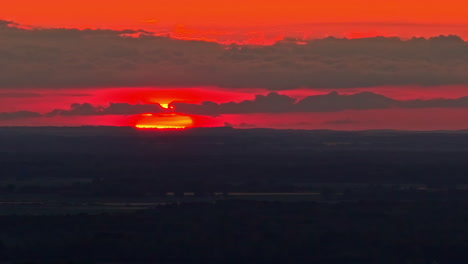 sunset light glows orange ball sinking behind mountain ridge, silhouette glow scenic