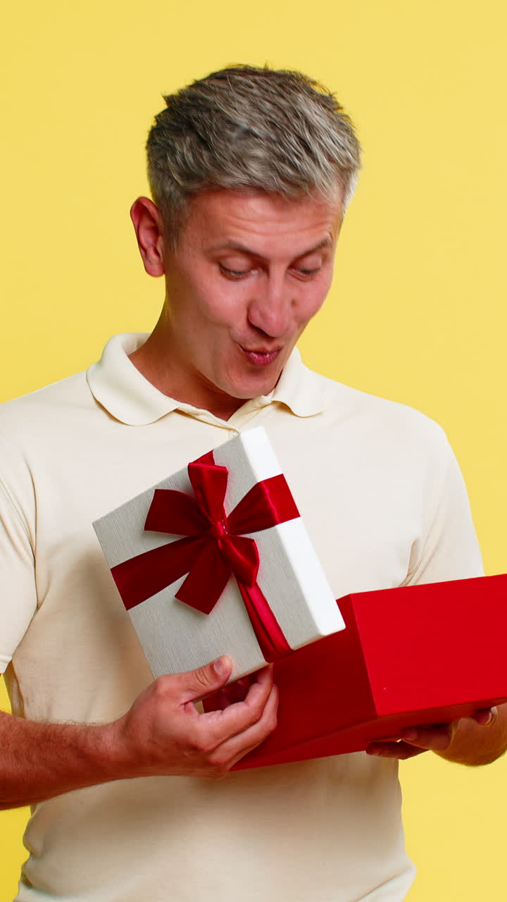 Adult man opening gift box freezing with amazed happy face showing surprise joy unexpected present