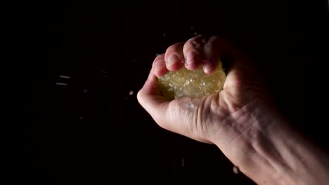 tiro de abajo hacia arriba: mano humana exprimiendo la mitad fresca de limón