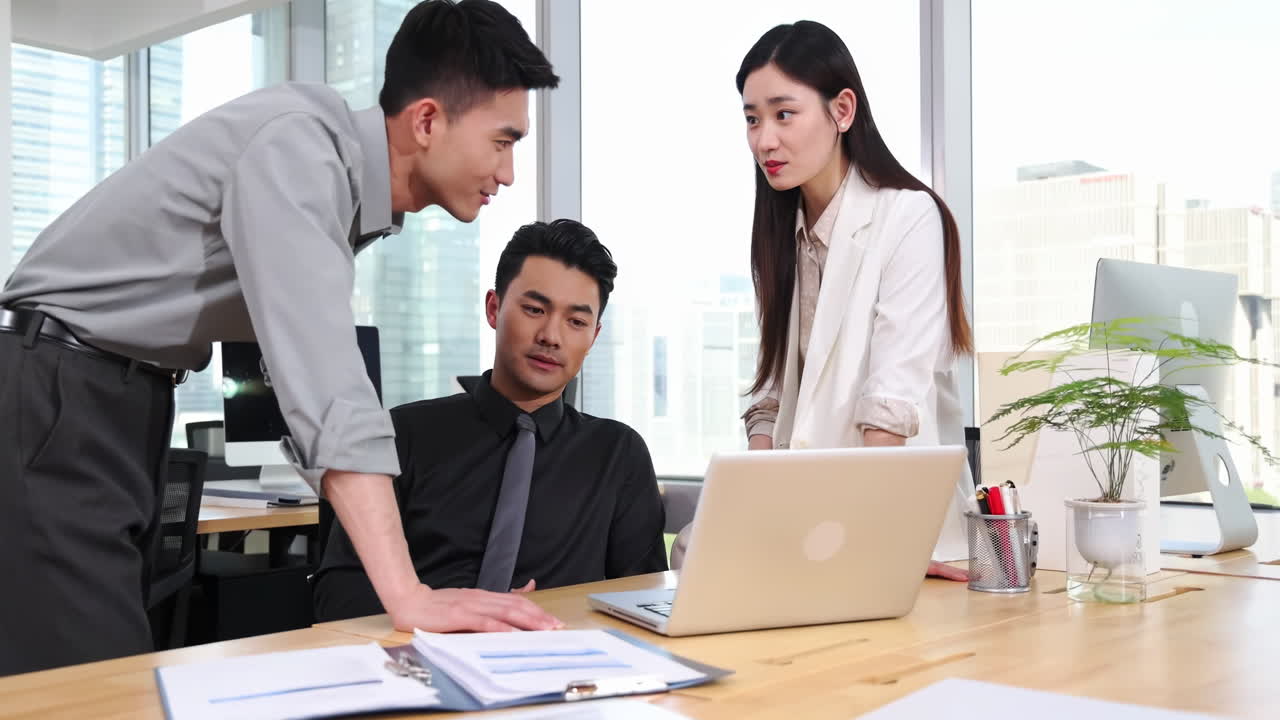チームワークが夢を叶える：プロのビジネス同僚が、デスクのコンピューターを見ながら、仕事について活発にコミュニケーションをとり、アイデアを交換し、チームワークと献身をアピールしています。