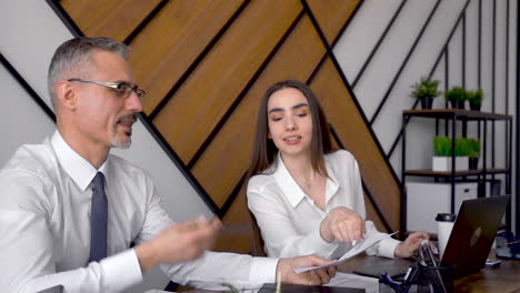 male employee showing document to his co worker while talk and laugh