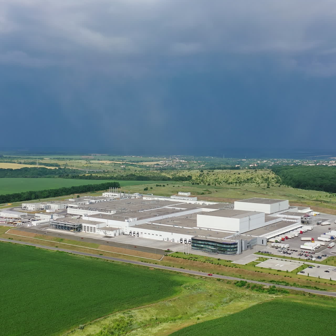 Large area of modern industrial complex. Aerial view to a big territory of manufacturing plant surrounded by nature. Camera moves bottom up.