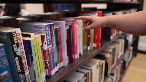 seleccionando a mano un libro de la estantería de la biblioteca