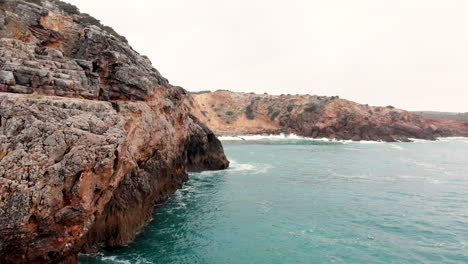 AERIAL:-Flying-close-to-the-cliffs-into-the-beach-in-portugal