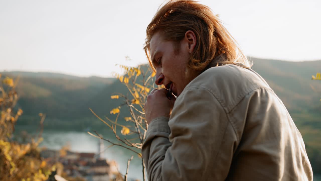 primer plano medio de un joven enrollando su cigarrillo en un paisaje impresionante, dürnstein
