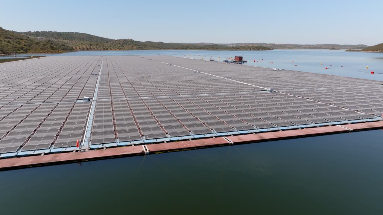volando por encima de una granja de paneles solares flotantes en un gran embalse