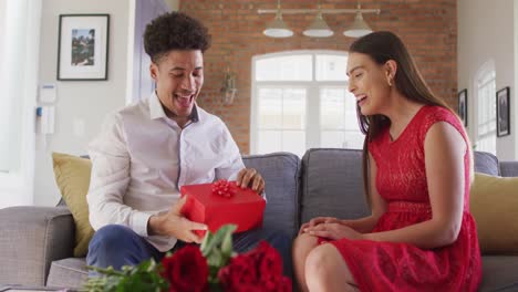 happy biracial couple celebrating valentine's day giving presents at home