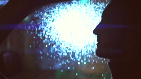 the attractive man sitting in the car on the rainy evening