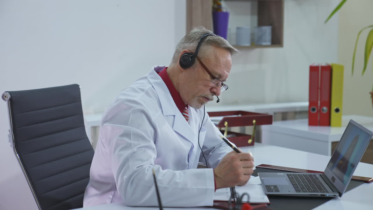 Doctor making an appointment of a patient online. Professional doctor in medical gown having a distant video call. Remote consultation.