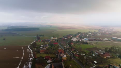 vista aérea de pájaro de un pequeño pueblo rural de casas y granjas en un día soleado de invierno