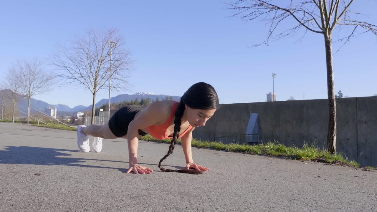 una joven magra en forma haciendo ejercicio de flexiones al aire libre de tiro ancho
