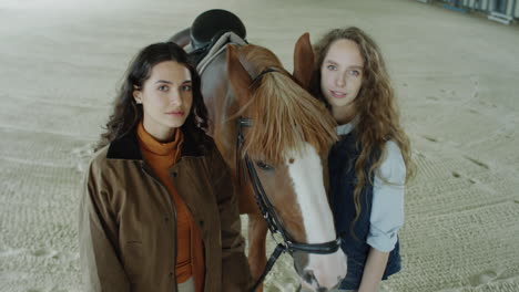 portrait of two pretty women with chestnut horse