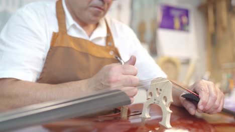 luthier installing sound post to violin