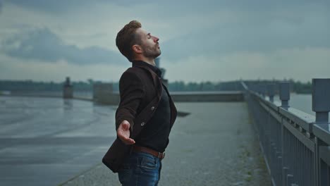 man enjoying a rainy day by the river