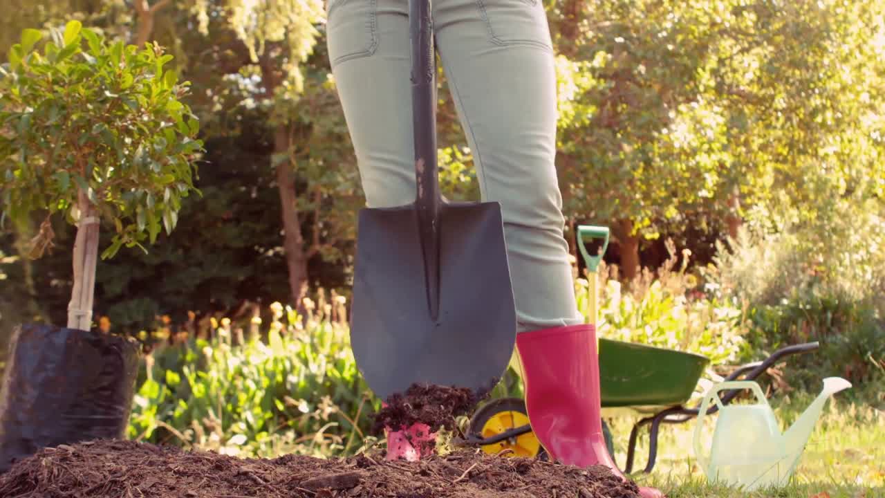 mujer con botas de goma rosadas usando una pala
