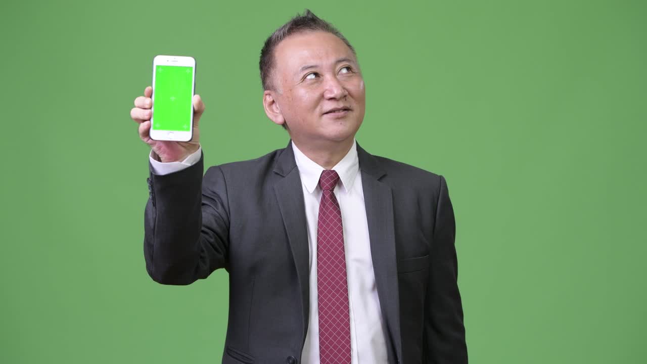성숙 한 일본인 사업가 가 카메라 에 전화 를 보여주고 있다