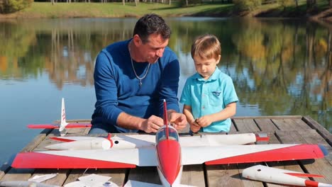 father and son assembling model airplane by the lake