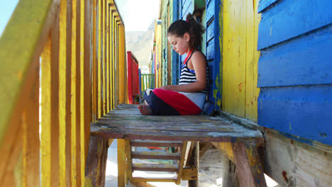 girl reading book near colorful beach hut