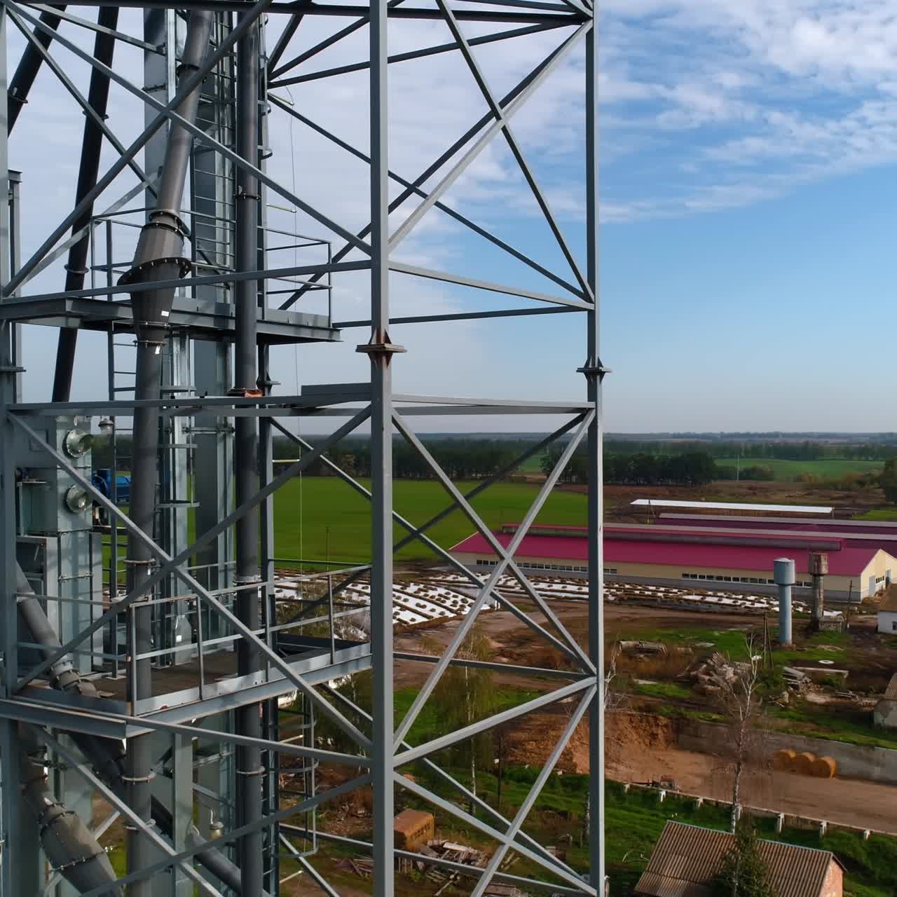 Steel frame in the industrial territory. Industrial plant in farmland. Grain elevators and metal equipment of a factory. View from above.