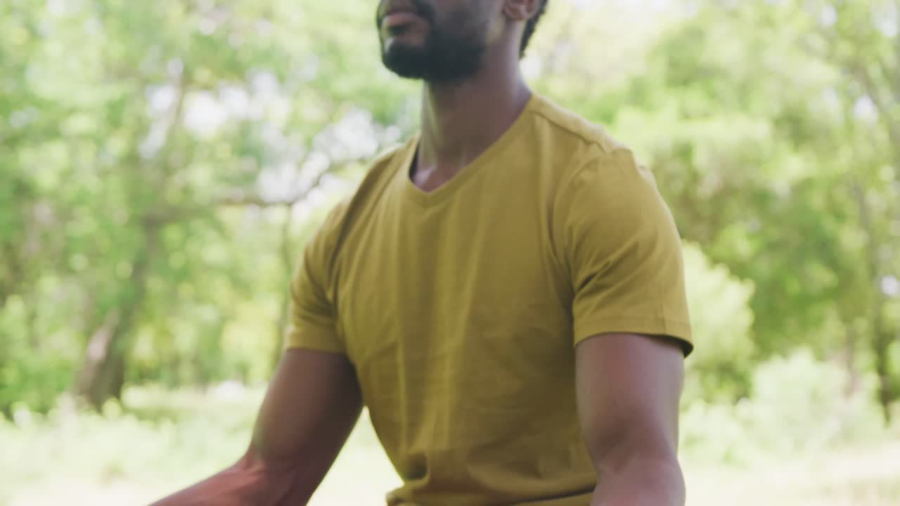 feliz hombre afroamericano sentado y meditando en el parque, cámara lenta