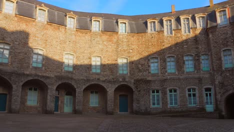 wide shot of interior stone courtyard with curved facade and soft morning shadows in chateau de boulogne-sur-mer