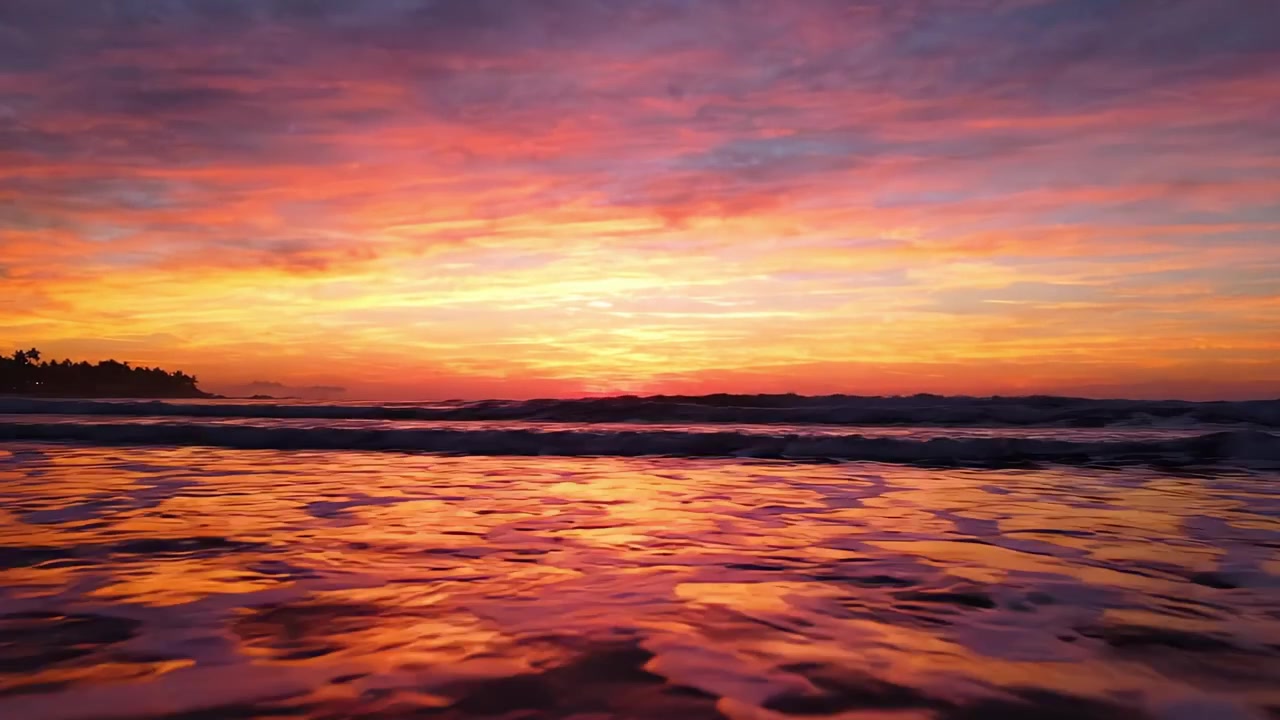 Betagende solnedgang over rolige havvande, dækket i levende nuancer af orange, pink og lilla, der skaber en fredfyldt aftenstemning ved kystlinjen